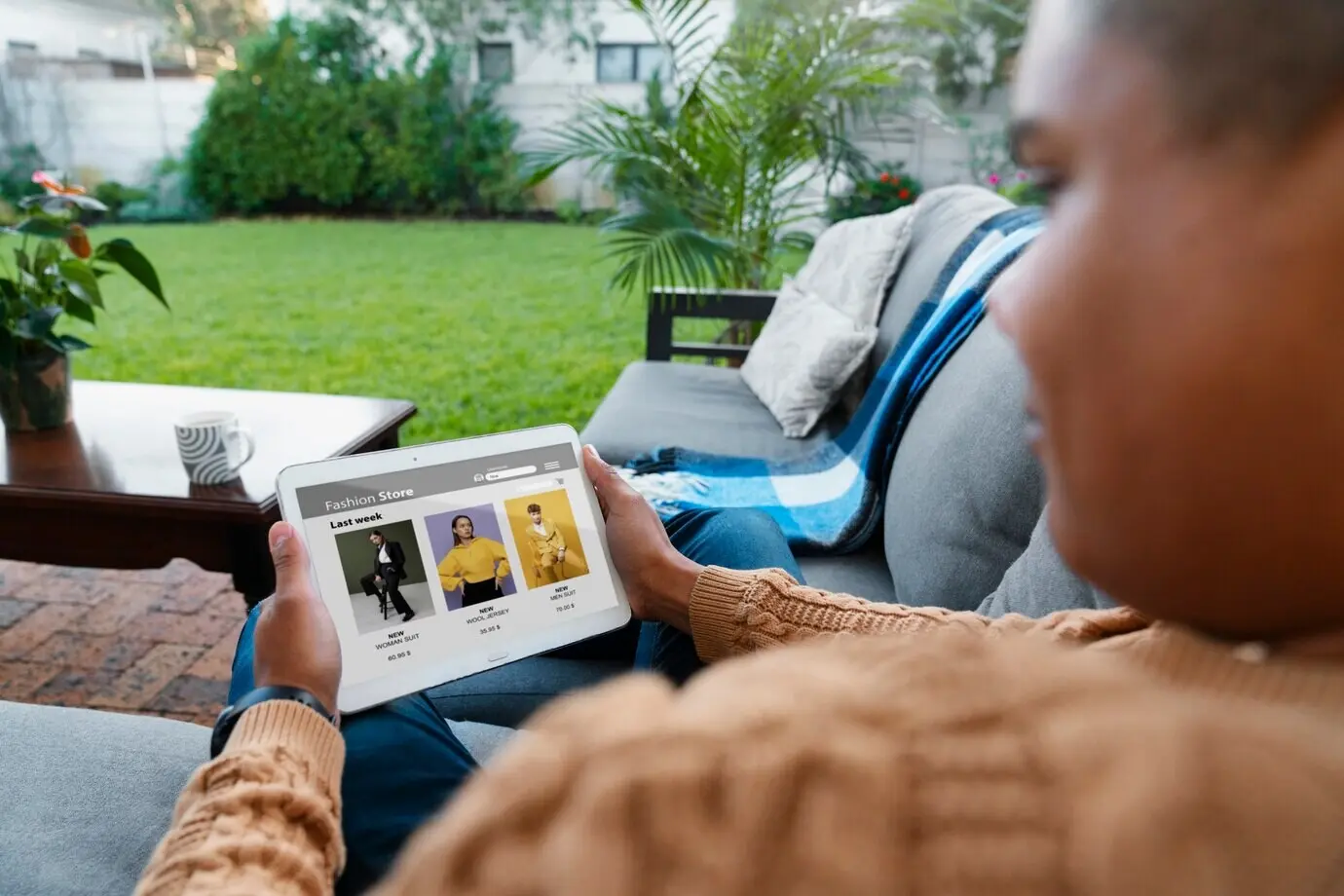 Rückenansicht eines Mannes, der im Freien ein Tablet benutzt.